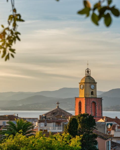 View of the old town of Saint-Tropez with the church poking over the horizon with the sea in the background.