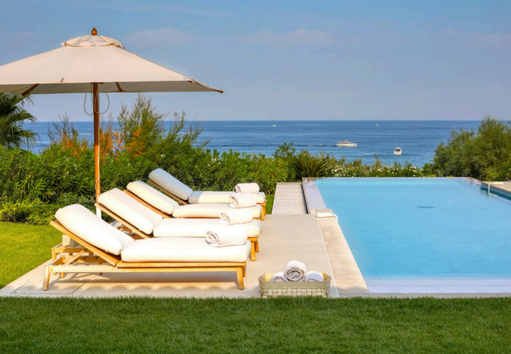 Piscine à débordement, transats et vue sur la mer